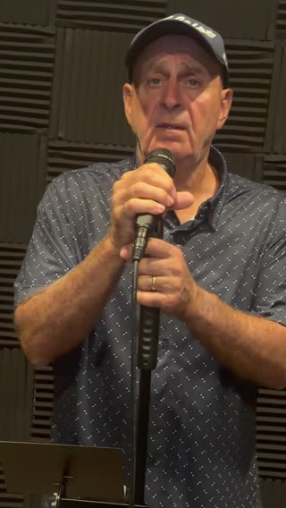 Mitch Moses singing into a microphone during a performance recording